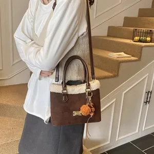 Detalle del bolso de cubo en gamuza marrón con borde de borreguito blanco y colgantes
