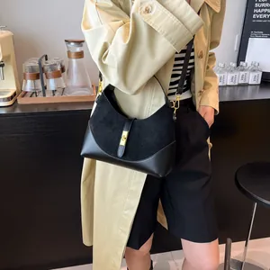 Detail of a black patchwork shoulder bag with gold buckle on a model in a trench coat