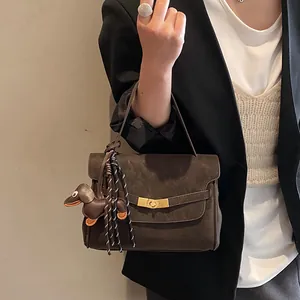 Detalle de bolso bandolera vintage mate con cierre dorado y colgante de cuero de teckel