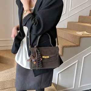 Detalle de bolso tote de cuero marrón mate con hebilla dorada y dije de perro en escalera
