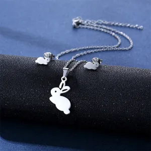 Macro detail of silver rabbit necklace and earrings set on a dark textured display