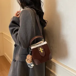 Détail du sac seau en daim marron avec bordure en fausse fourrure blanche et ourson