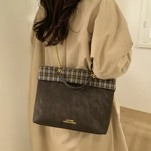 Detail der Vintage-Karo-Tasche mit Goldkette und geprägtem LEATHER-Logo auf Wildleder