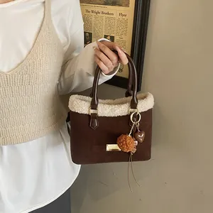 Detalle de bolso de ante café con ribete de borrego sintético y asa de cuero