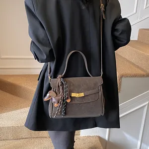 Detalle del bolso de cuero mate marrón oscuro con broche dorado y colgante de perro