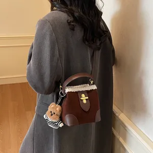 Détail du sac seau en daim marron avec bordure en peau de mouton et breloque ourson