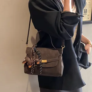 Detalle de bolso tote marrón mate con cierre dorado y colgante de perro teckel