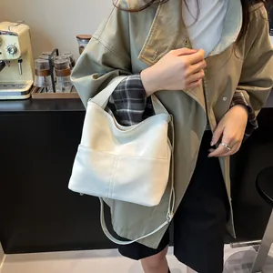 Dettaglio della borsa tote bianco crema con cuciture verticali e tasca frontale sulla tracolla