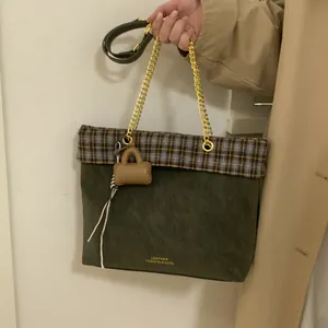 Detail der Vintage grünen Tragetasche mit Karomuster und goldener Kettenriemen-Griff