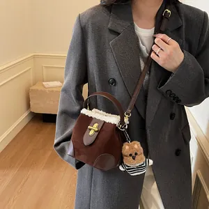 Détail d'un sac seau vintage en daim marron avec bordure en molleton et charm ours