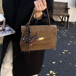 Detalle del bolso de mano marrón oscuro mate con cierre dorado y colgante de caballo