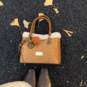 Detalle de bolso tipo cubo de felpa con placa dorada y hojas de otoño en el suelo