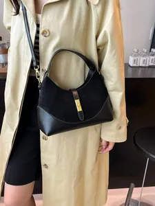 Women's black minimalist half-moon crossbody bag with gold metallic lock and suede detail