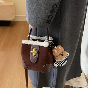 Détail du sac seau en daim marron avec bordure en laine blanche et fermoir doré tournant