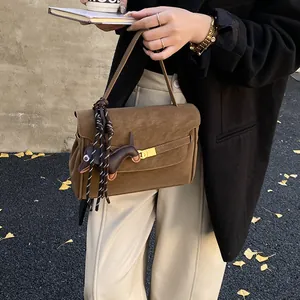 Detalle de bolso tote vintage en ante marrón con cierre metálico y colgante de teckel