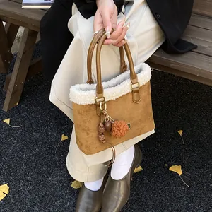 Detalle del bolso de peluche marrón con ribete de piel sintética y colgante de cuentas