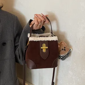 Détail du sac seau en daim marron avec bordure en fourrure blanche et fermoir doré