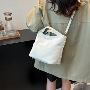 Vista dettagliata della borsa tote in pelle bianca con piedini in metallo e tracolla