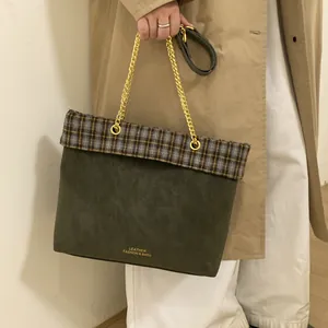 Detail der Vintage-Grünen Ledertasche mit Karomuster und Goldkette, gehalten von Model