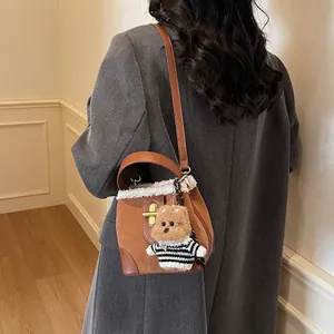 Détail du sac seau rétro en daim avec bordure en fourrure et breloque petit ours