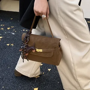 Detalle de bolso tote vintage de ante marrón con cierre dorado y adorno de perro