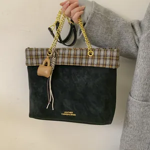 Detail der Vintage-Karoverzierung an einer schwarzen Wildleder-Tote mit goldener Kette
