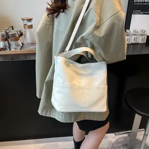 Dettaglio di una borsa tote bianca in ecopelle con una tasca frontale dal design minimal