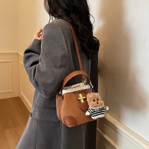 Détail du sac seau en daim caramel avec garniture en peau de mouton et breloque chien