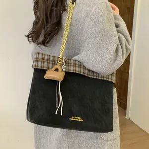 Detail der Vintage-Tote-Bag mit Karomuster, Goldkette und Quastenanhänger am Modell