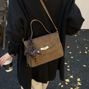Bolso bandolera de cuero marrón mate con cierre dorado y colgante en forma de perrito
