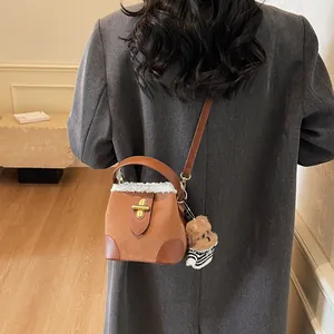 Détail du sac seau en daim marron avec bordure en peluche et breloque ours mignonne