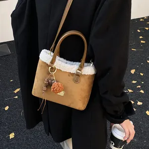 Detalle de bolso de ante marrón con ribete de borreguito y colgante de corazón suave
