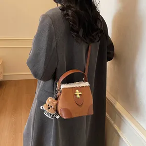 Détail du sac seau en daim avec bordure en peau lainée et pendentif ours en peluche