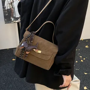 Detalle del bolso tote de ante marrón moka con hebilla dorada y colgante de perro de cuero
