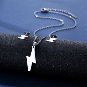Macro detail of silver lightning bolt necklace and earring set on black leather stand