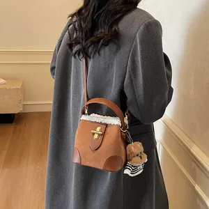 Détail du sac seau marron en daim avec bordure en peau de mouton et breloque chiot