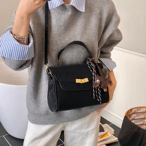 Detalle del bolso tote negro mate con cierre dorado y colgante de perro de dibujos