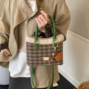 Detalle del bolso tipo cubo de cuadros con ribete de felpa blanca y asas de cuero verde
