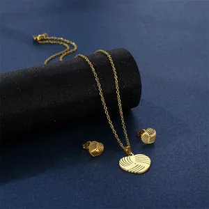 Goldenes Edelstahl-Schmuckset mit Herz-Halskette und Ohrringen auf blauem Grund
