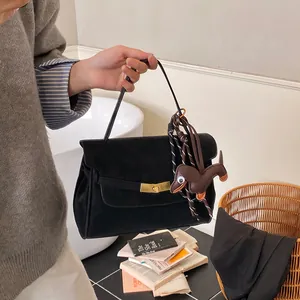 Detalle de bolso tote de ante negro con cierre dorado y accesorio de amuleto de perro teckel