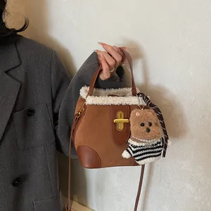 Détail du sac seau en daim marron avec bordure en laine blanche et breloque ours
