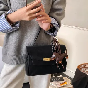 Detalle de bolso negro mate con cierre giratorio dorado y colgante de perro de cuero