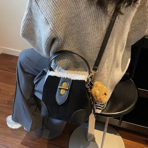 Détail du sac seau en daim noir avec bordure en fausse fourrure blanche et breloque ours