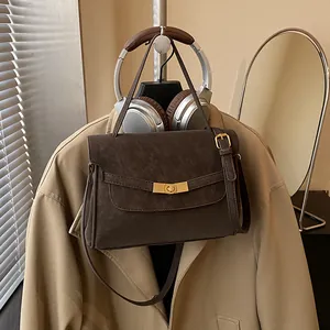 Detalle del bolso tote marrón mate vintage con hebilla dorada y correa ajustable