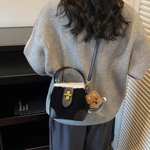 Détail du sac seau vintage en daim noir avec bordure en peau lainée blanche et breloque ours