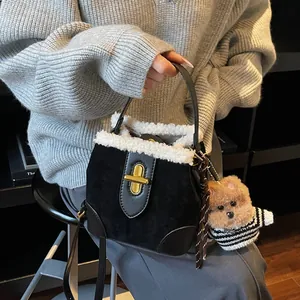Détail du sac seau en daim avec bordure en fourrure blanche, fermoir doré et ours