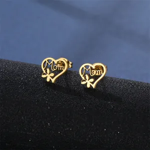 Golden heart-shaped stainless steel MOM studs with floral detail on dark stand