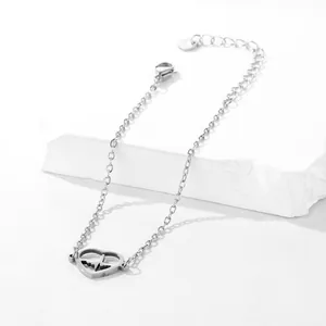 Detail of silver heart heartbeat charm bracelet with adjustable chain on white stone
