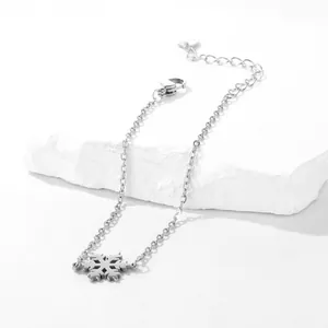 Detail of silver stainless steel snowflake bracelet with lobster clasp on white stone