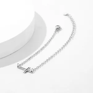 Vue détaillée du bracelet croix en acier inoxydable argenté avec breloque cœur et fermoir homard